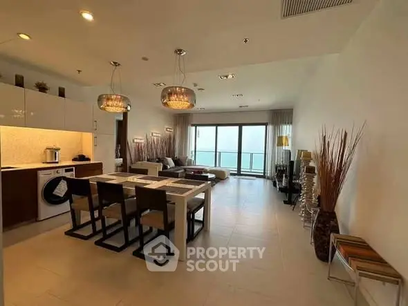 Spacious modern living room with dining area and ocean view balcony.