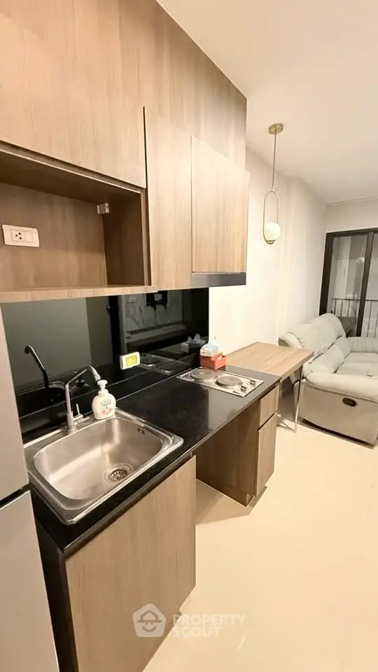 Modern kitchen with sleek cabinetry and cozy living area in a stylish apartment.