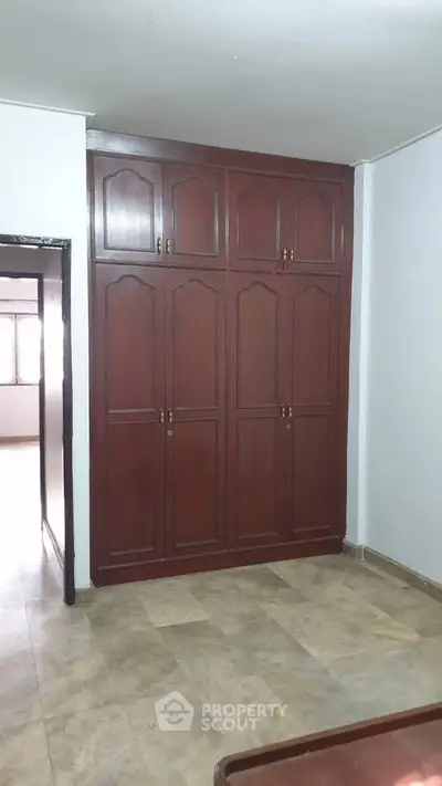 Spacious room with elegant wooden wardrobe and tiled flooring