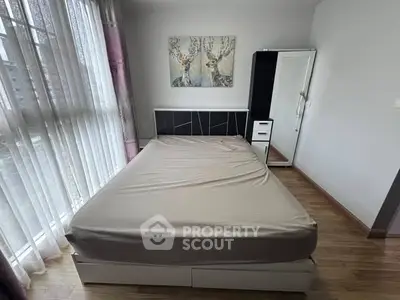 Cozy bedroom with large window and modern decor, perfect for relaxation.