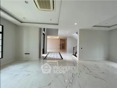 Spacious modern living room with marble flooring and elegant lighting in luxury home.