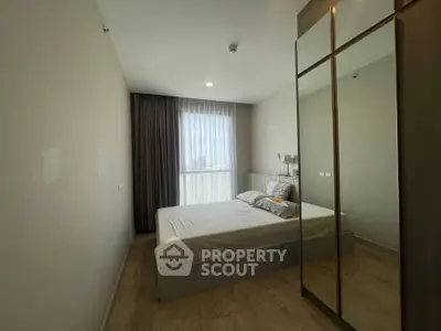 Modern bedroom with large mirrored wardrobe and city view window, perfect for urban living.