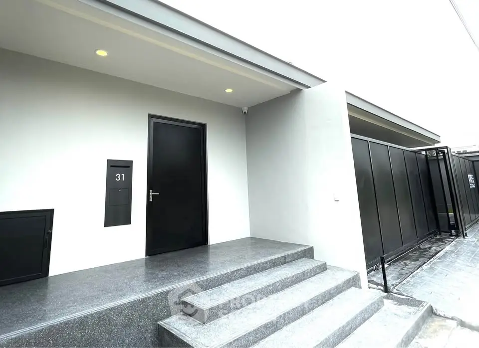 Modern minimalist building entrance with sleek black door and steps