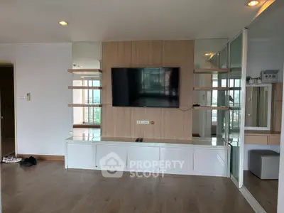 Modern living room with wall-mounted TV and sleek storage unit in a stylish apartment.