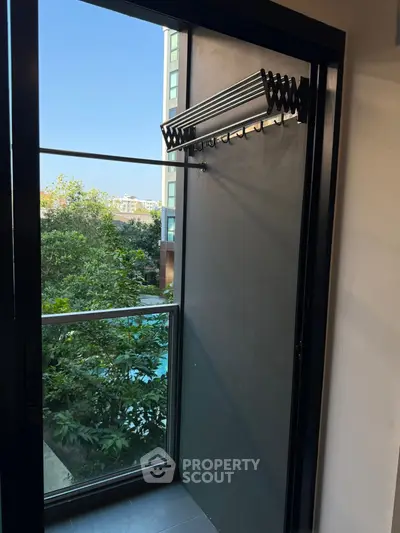 Modern apartment balcony with sleek glass railing and lush green view