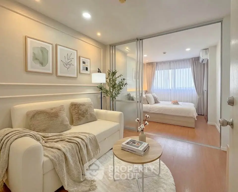 Modern apartment interior with cozy living room and elegant bedroom separated by glass doors.