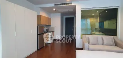 Modern studio apartment with open layout, featuring a kitchenette, washing machine, and cozy seating area.