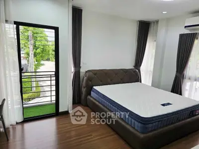 Spacious bedroom with large windows and balcony access, featuring a modern bed and elegant curtains.
