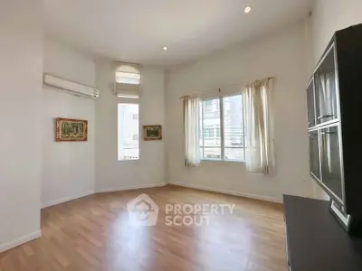 Spacious living room with wooden flooring and large windows in a modern apartment.