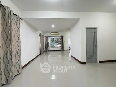 Spacious living room with large windows and elegant curtains, perfect for natural light and comfort.