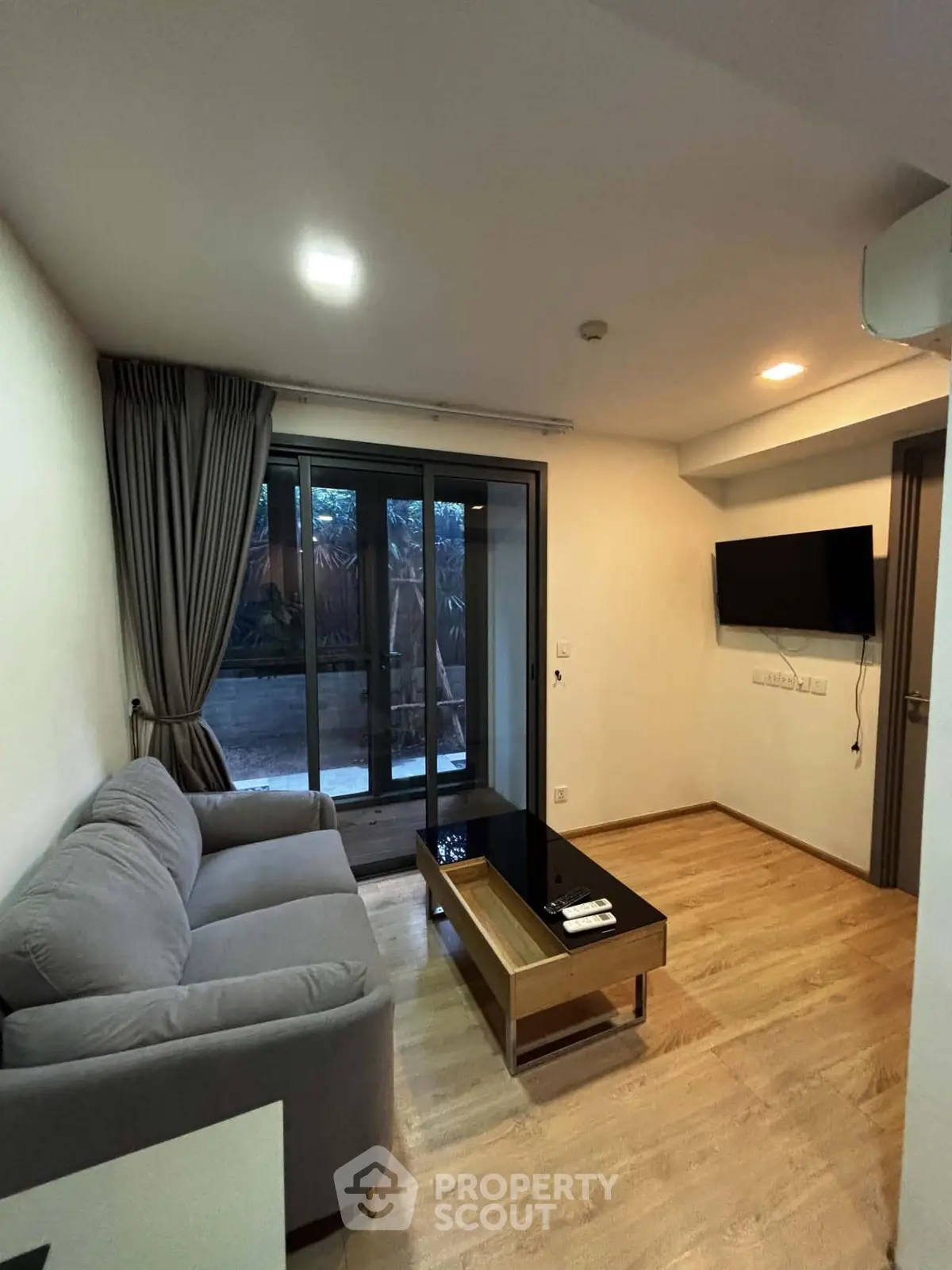 Modern living room with sleek design and garden view, featuring a cozy sofa and wall-mounted TV.