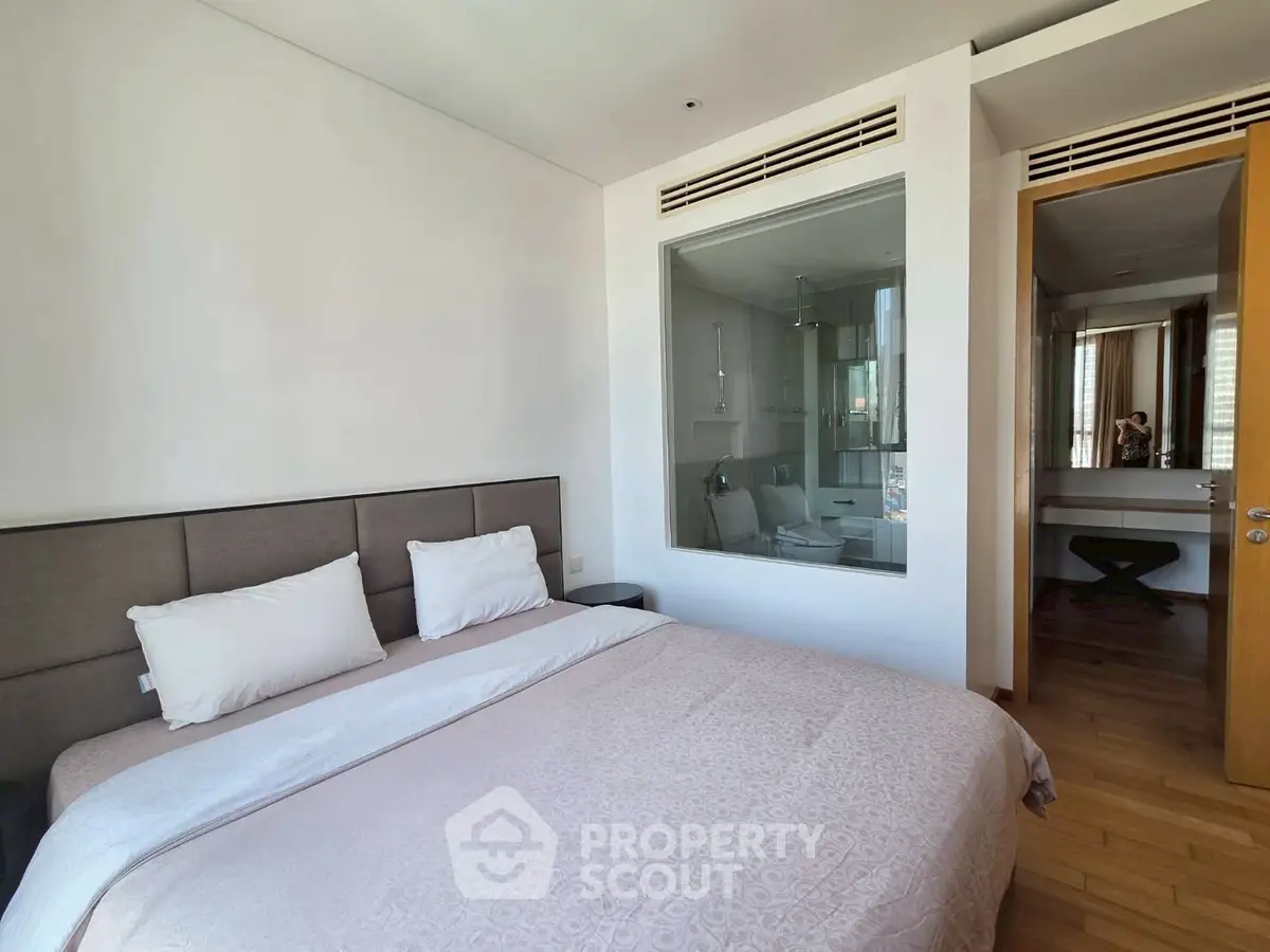 Modern bedroom with ensuite bathroom and wooden flooring in luxury apartment