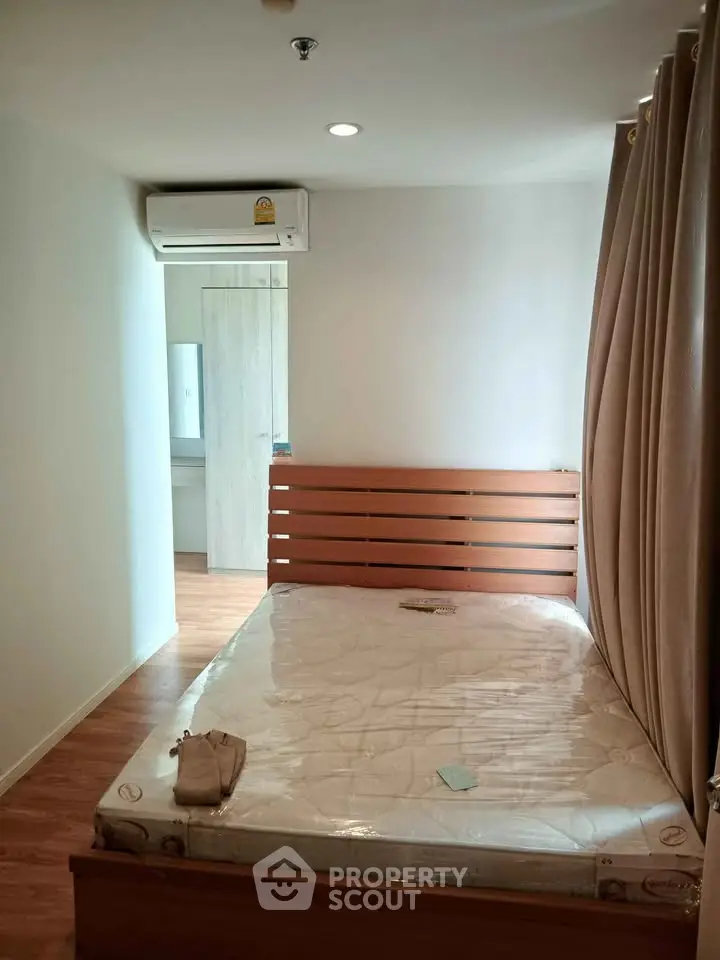 Cozy bedroom with wooden flooring and air conditioning in modern apartment.