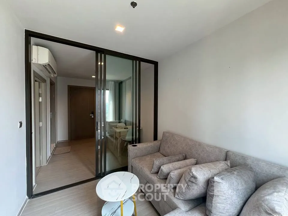 Modern living room with sliding glass doors and cozy gray sofa in a stylish apartment.