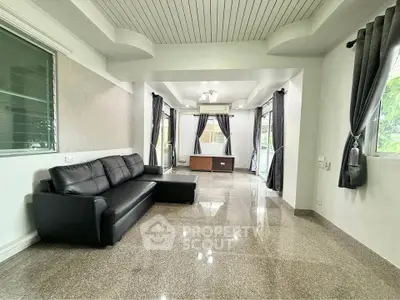 Spacious modern living room with sleek black sofa and large windows for natural light.