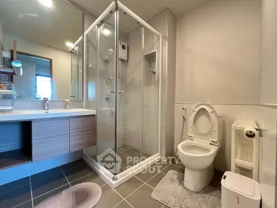 Modern bathroom with glass shower and sleek vanity in contemporary home.