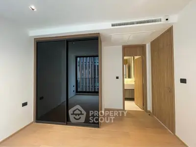 Modern bedroom with sleek mirrored closet and wooden flooring