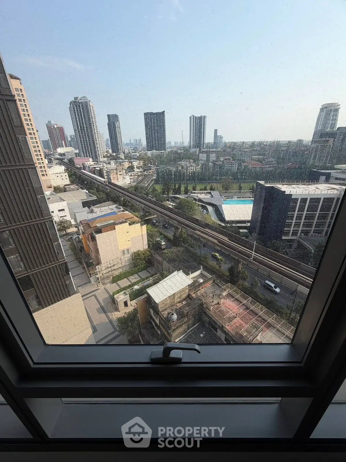 Stunning cityscape view from high-rise window, showcasing urban skyline and railway below.