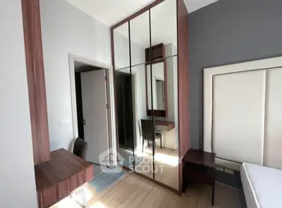 Modern bedroom with mirrored wardrobe and sleek wooden furniture