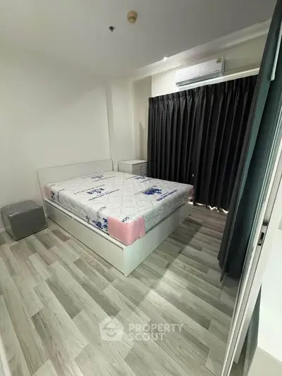 Modern bedroom with sleek flooring and air conditioning, featuring a comfortable bed and stylish curtains.