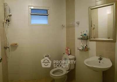 Spacious bathroom with modern fixtures and neutral tiles, featuring a shower and wall-mounted mirror.