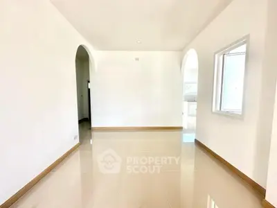 Spacious bright room with arched doorways and glossy tiled floor