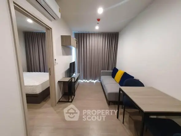 Modern apartment living room with cozy sofa and dining area, adjacent to a bedroom with stylish decor.