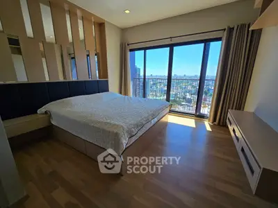 Spacious bedroom with large windows offering stunning city views and modern wooden flooring.