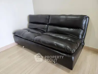 Sleek black leather sofa in a modern living room with wooden flooring.