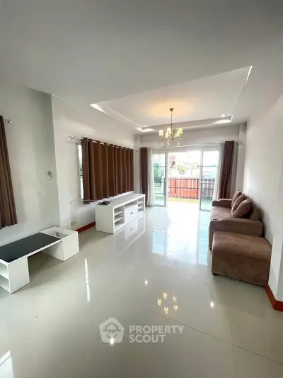 Spacious living room with modern decor and large windows leading to balcony