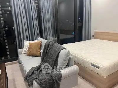 Modern studio apartment with cozy bed and stylish sofa, featuring floor-to-ceiling windows and city views.