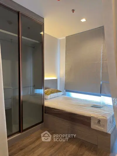 Modern bedroom with sleek design, featuring a single bed and mirrored wardrobe, perfect for urban living.