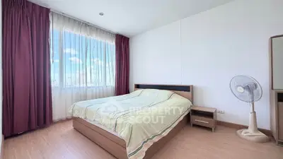 Spacious bedroom with large window and city view, featuring modern furniture and elegant curtains.