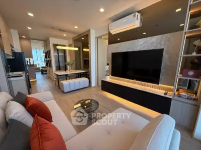 Modern living room with stylish decor and large TV, open layout leading to dining area