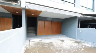 Modern townhouse entrance with wooden doors and covered parking area