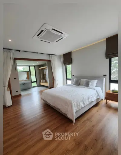 Spacious modern bedroom with wooden flooring and large windows