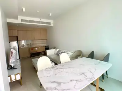 Modern open-plan living room with stylish kitchen and dining area, featuring sleek furniture and bright lighting.