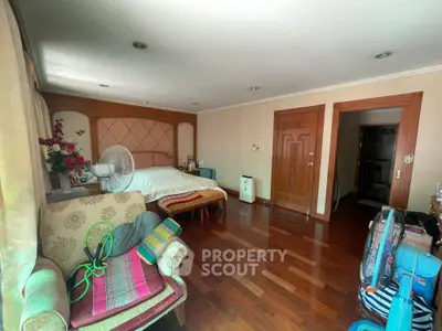 Spacious bedroom with wooden flooring and cozy seating area