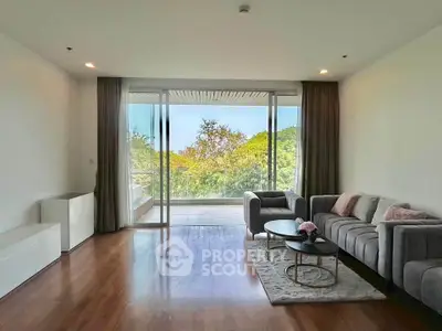 Spacious living room with modern decor and large glass doors opening to a scenic balcony view.