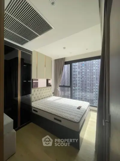Modern bedroom with large window and city view in high-rise apartment