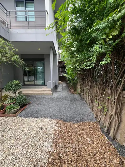 Charming modern home exterior with lush greenery and gravel pathway