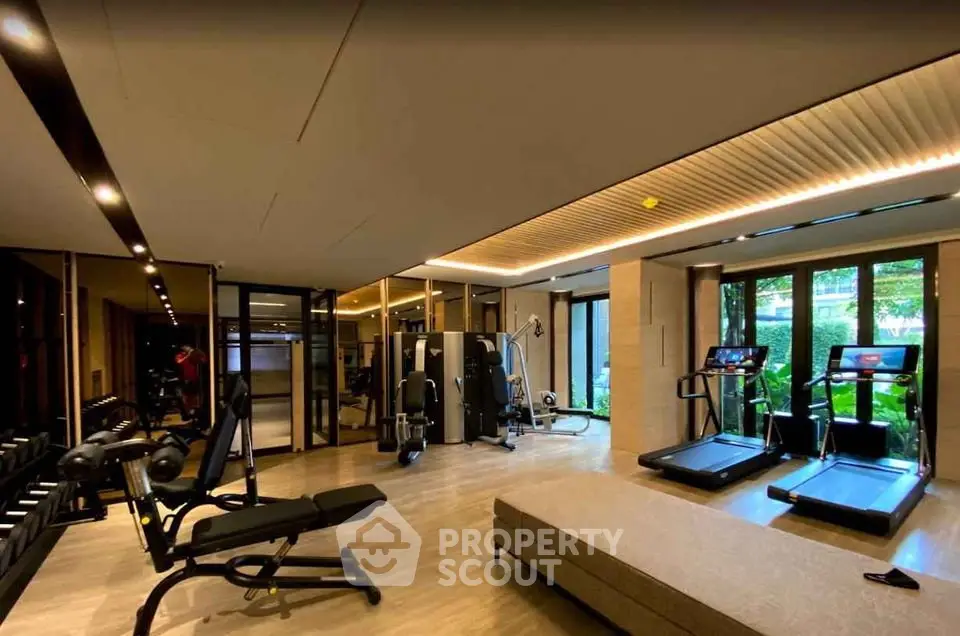Luxurious gym with modern equipment and large windows in upscale residential building.