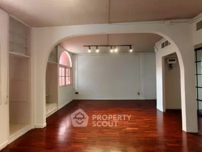 Spacious living room with elegant arches and rich wooden flooring, perfect for modern living.