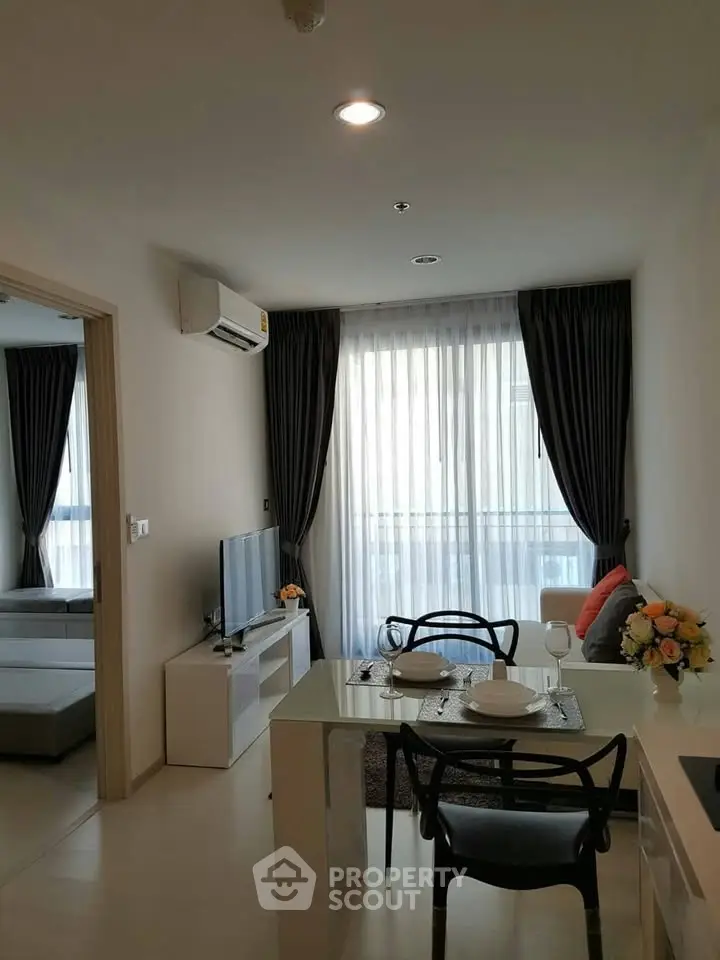 Modern living room with dining area, featuring elegant decor and natural light through large windows.