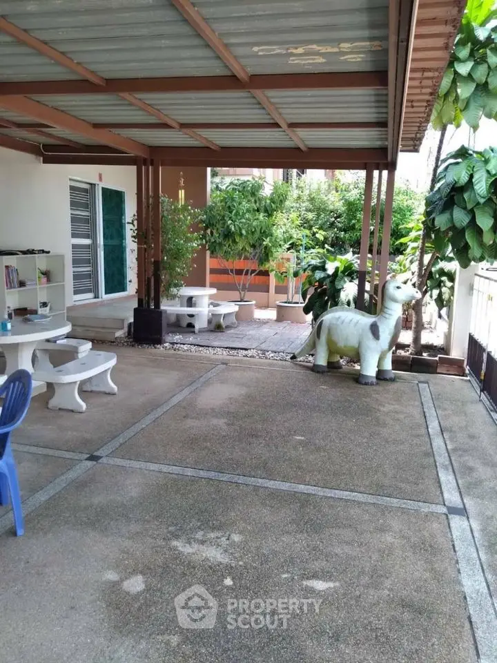 Charming outdoor patio with unique dinosaur sculpture and lush greenery.