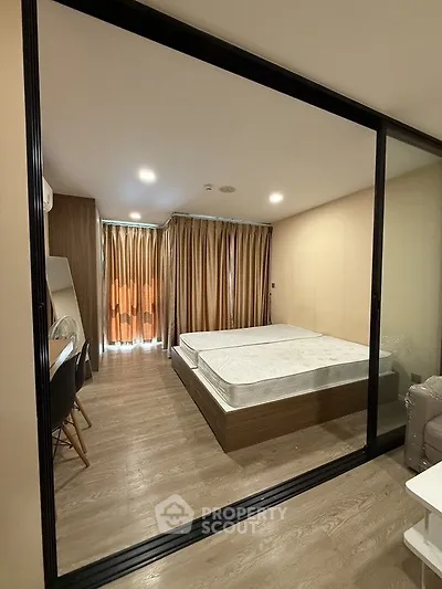 Modern bedroom with glass partition and wooden flooring in stylish apartment.