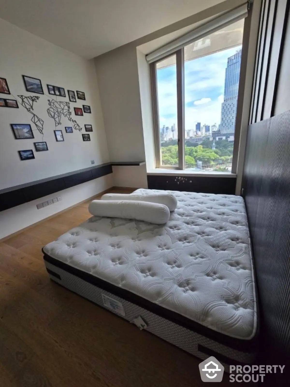 Spacious bedroom with large window offering stunning city view and modern decor.