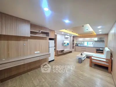 Spacious modern living room with open kitchen layout and stylish wooden flooring.