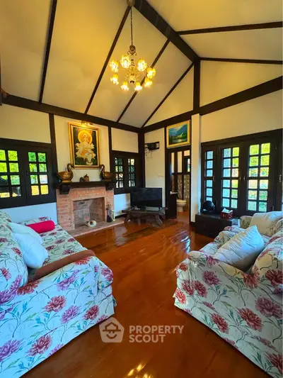 Charming living room with high ceilings, wooden floors, and cozy floral sofas in a rustic home.
