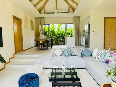 Spacious living room with modern decor and large windows overlooking lush greenery.